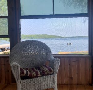 A wicker chair in front of a window with water view.