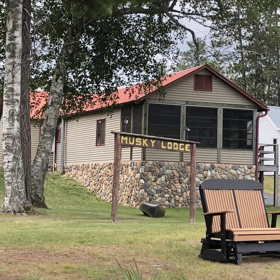 2021 Jack Pine pic1 A wooden bench sitting in front of a cabin.